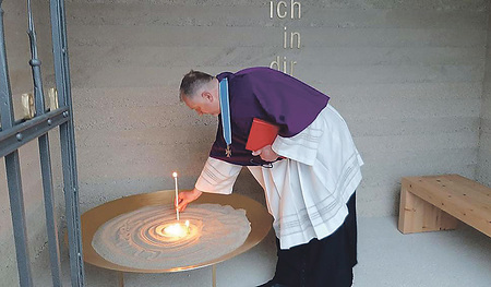 Pfarrer Wolfgang Schnölzer entzündet eine Kerze in der neuen Gedenkstätte.  