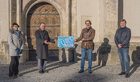 Pfarrer P. Severin (links) und Johannes Bachhalm halten den Scheck.