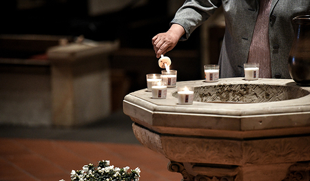 „Das Glaubensbekenntnis verdankt sich der Feier der Taufe“, sagt der Theologe Franz Gmainer-Pranzl.  Im Bild: Eine Frau entzündet eine kleine Kerze am Taufbecken bei der Feier der Osternacht.