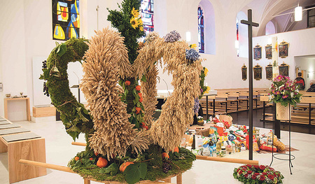 Vor der Erntekrone findet sich ein Berg an Lebensmitteln.  