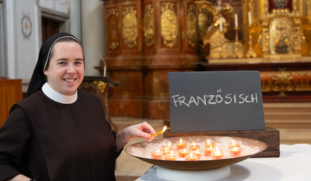 Sr. Helena Fürst, Ordensfrau bei den Elisabethinen, entzündet eine Kerze für Maturant:innen, die ihre Französisch-Matura schreiben.
