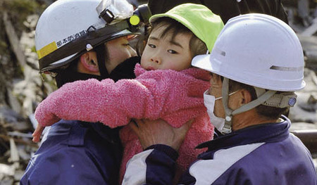 Rescue workers hold a girl they rescued from a building after a tsunami and earthquake in Kesennuma City, Miyagi Prefecture, in northeastern Japan March 12, 2011. Japan confronted devastation along its northeastern coast on Saturday, with fires ragin