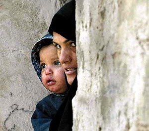 An Iraqi woman holds her child as she looks out her house at the United Nations arms inspection team, before they searched the nearby al-Sawari facility for weapons of mass destruction, 30 km north of Baghdad, December 16, 2002.  U.N. arms teams set 