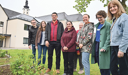 Die Jungscharleitenden Manuel Steiner und Sarah Kowatschek (von links) zeigen den Besucher:innen aus Armenien, Armen Martirosyan und Mariam Mardanyan, sowie weiteren Gästen und Organisatorinnen der Begegnung ihre Beete mit den Beerensträuchern.   
