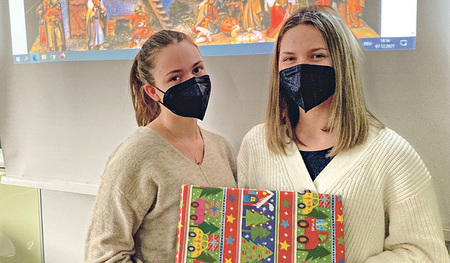 Zwei Schülerinnen mit einem Weihnachtspaket. 