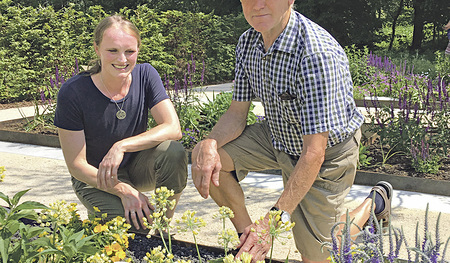 Zwei Teilnehmende an der Führung durch den Schöpfungsgarten schauen sich die Pflanzen genauer an.  