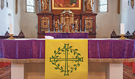 Blick in den Altarraum der Pfarrkirche Obernberg, mit einer Textilikone nach der Darstellung von Andrej Rublëv aus dem Jahr 1411 und dem Logo der von Pfarrer Wiesinger initiierten Stephanusrunde (vorne)    