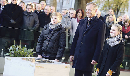 Landeshauptmann Thomas Stelzer (Mitte) hat mit Schulkindern vor dem Landhaus einen Gedenkstein enthüllt, der bleibend an das Jubiläum erinnern soll.   