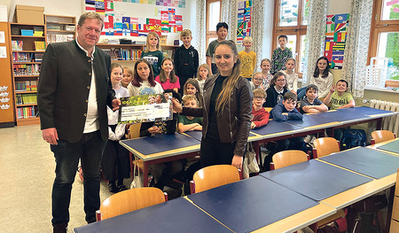 Michael Koller von der Helvetia Versicherung übergibt den Betrag an die Kreuzschwestern-Volksschule Linz.  